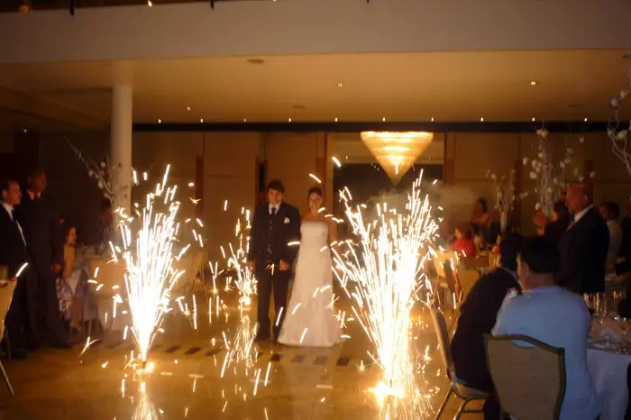 Fogos indoor com gerbs dourados disparando faíscas em cerimônia de casamento